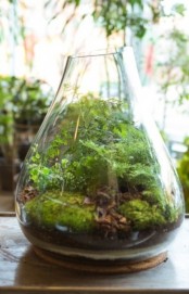 an irregular vase with moss, driftwood and greenery is a lovely and fresh idea of a spring decoration to rock