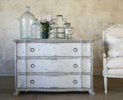a whitewashed dresser and a whitewashed and white upholstery chair look very stylish and beautiful in a refined vintage space
