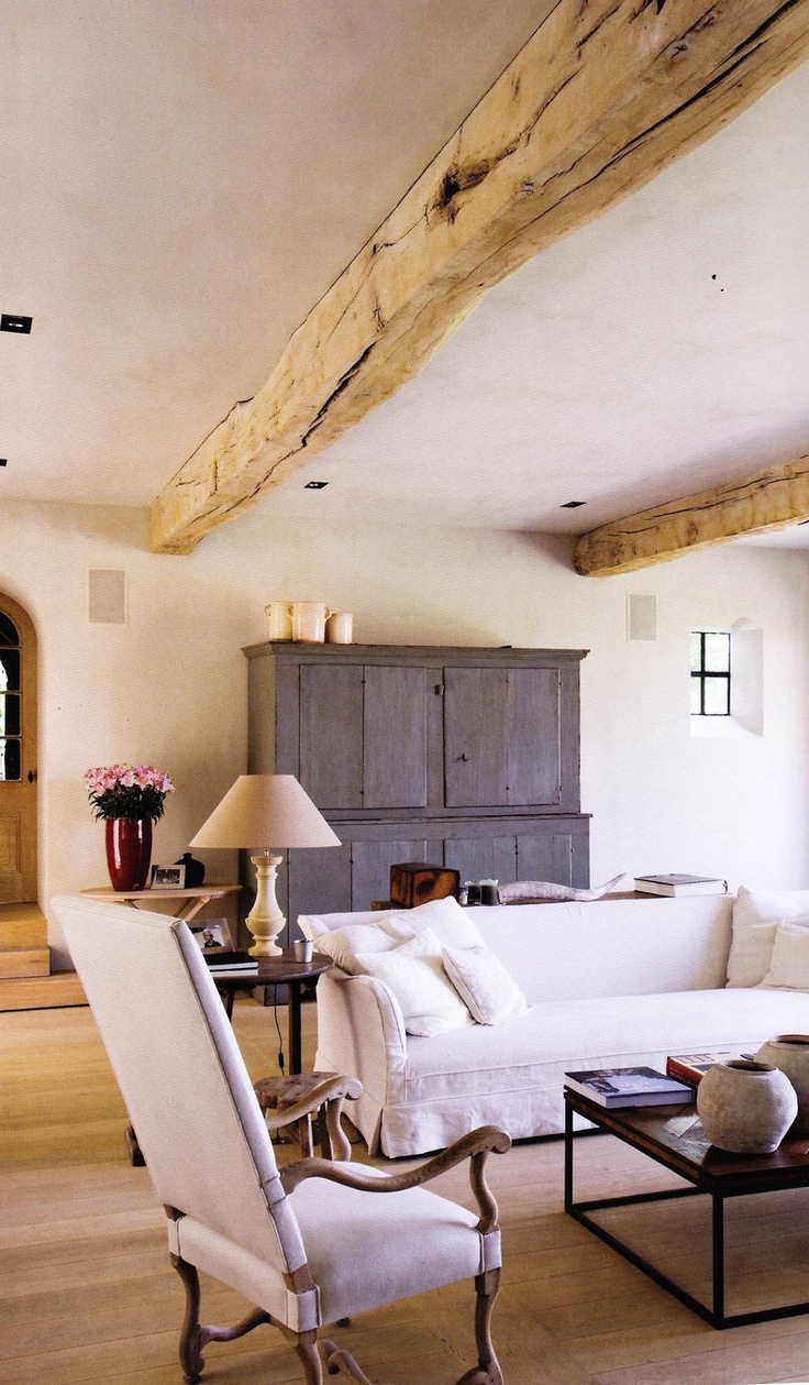 Wooden beams on the ceiling and a buffet of reclaimed wood make this living room feel rustic