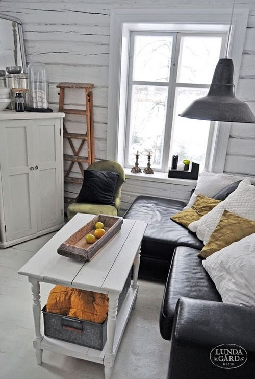 a rustic Nordic space with whitewashed wooden walls, retro furniture and a metal lamp over it