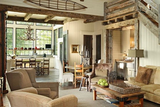 a rustic living room done with shiplap and reclaimed wood, wooden beams and a wooden staircase plus retro furniture