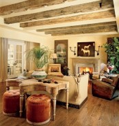 a chic rustic space with wooden beams on the ceiling, a refiend fireplace and shabby chic furniture