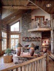 a cozy rustic cabin living room done with plenty of wood and stone, with a fireplace, wooden plates, a tree stump table and cozy furniture