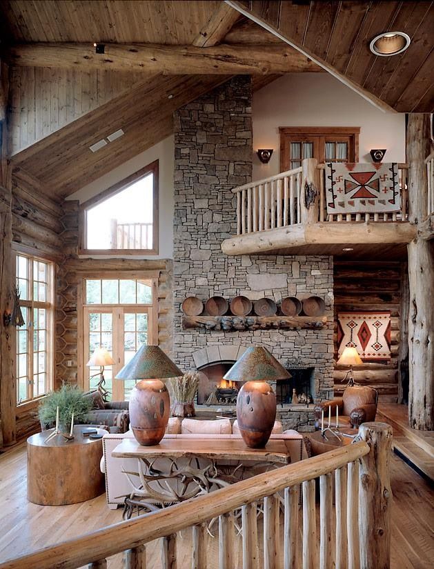 A cozy rustic cabin living room done with plenty of wood and stone, with a fireplace, wooden plates, a tree stump table and cozy furniture