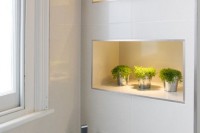 a contemporary bathroom with lit up niche shelves that feature storage and display space and add decorative value
