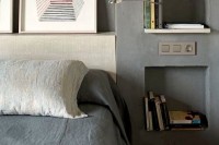 an industrial bedroom with concrete walls and niche shelves instead of nightstands, this is a great alternative to usual shelves and they look sleek