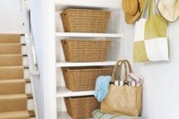 a cottage entryway with niche shelves and woven boxes plus an upholstered bench is a cozy and cute space with plenty of storage