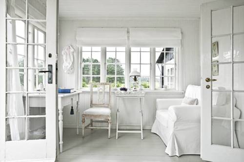 All-white Scandinavian room with a bunch of windows and a glass door.