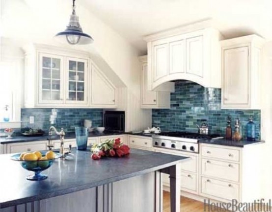 an ocean-inspired kitchen with neutral shaker style cabinets, a gorgeous blue tile backsplash, a blue pendant lamp and a midnight blue kitchen island