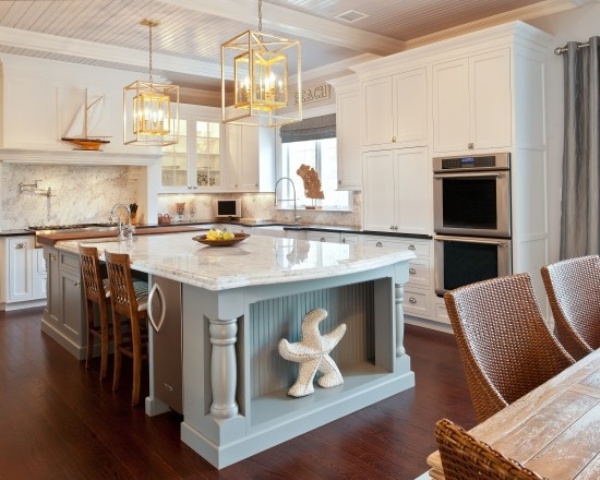 A fresh take on a classic beach kitchen with white shaker style cabinets, white tiles, a light blue kitchen island and some beach decor   a starfish and a boat