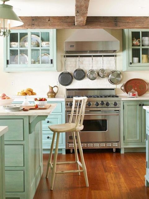 An aqua colored kitchen with shaker style cabinets, white stone countertops, stainless steel appliances and a white tile backsplash