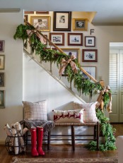 a lush evergreen garland with red berries and burlap bows is a cool and lovely decor idea for Christmas, style your banister with it