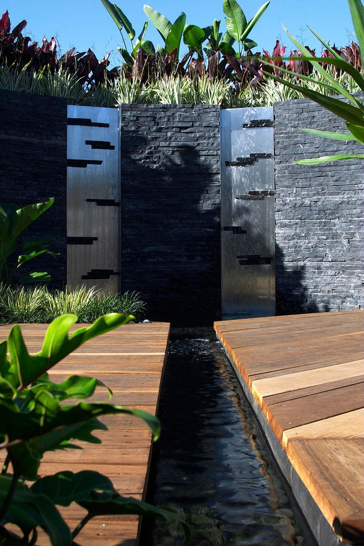 Contemporary metal water walls framed in black stone.