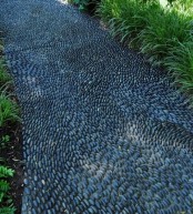 a black pebble garden pathway with a chaotical pattern is a creative and bold idea that makes statement both with color and pattern