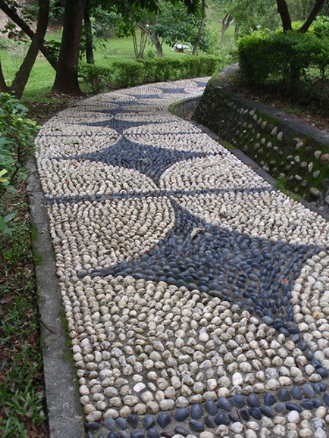 a very bold and eye-catchy neutral and grey pebble pathway with creative patterns and brick lining up