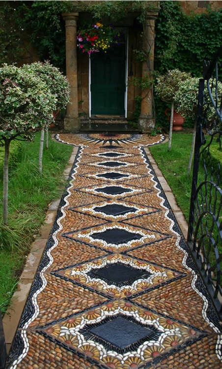 a super bold and unique pebble garden path with a geometric and floral pattern in yellow, white and black