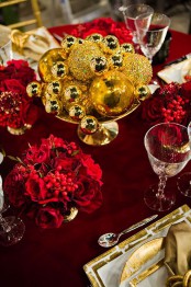 a refined deep red and gold Christmas tablescape with an ornament centerpiece and red blooms plus gold chargers and cutlery
