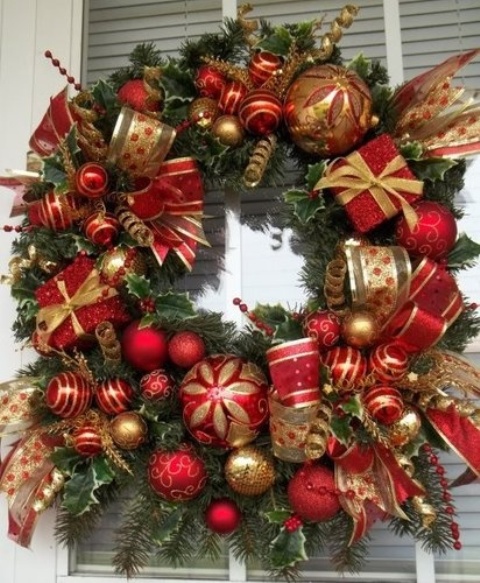 a chic and refined Christmas wreath of red and gold ornaments and ribbons and evergreens is a cool idea