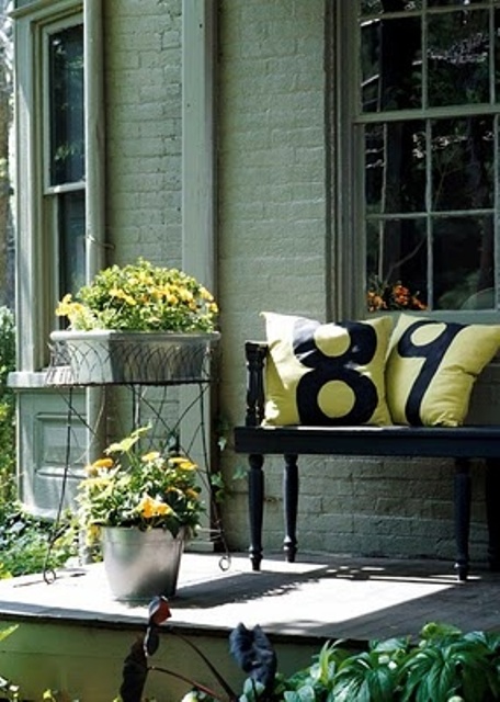 Yellow blooms in buckets and bright yellow pillows on the bench to make the porch feel more spring like