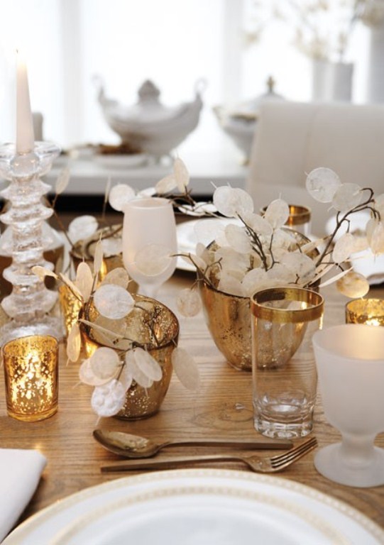 a refined gold and white Christmas tablescape with frosted glasses, lunarias, white porcelain and gold candleholders