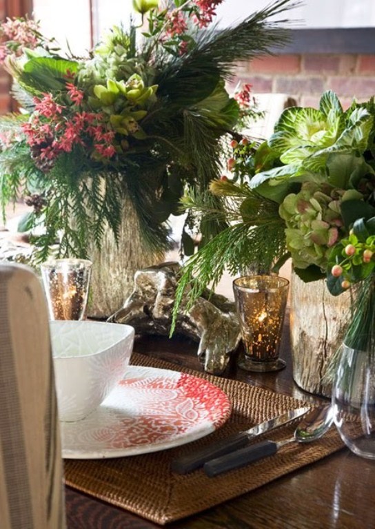 A vintage inspired Christmas tablescape with woven placemats, printed red and white porcelain, lush greenery and florals, mercury glass candleholders