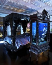 a large aquarium enclosed into a refined and chic black dresser to match the room design