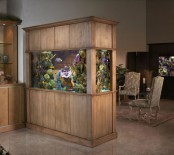 an aquarium clad in stained wood is a nice space divider that separates the living room and the entryway
