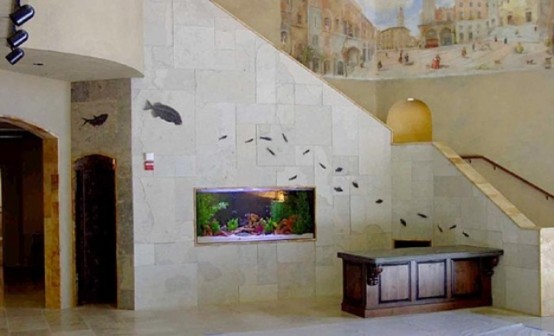 an aquarium built into a stone staircase is a stylish decor feature for this foyer