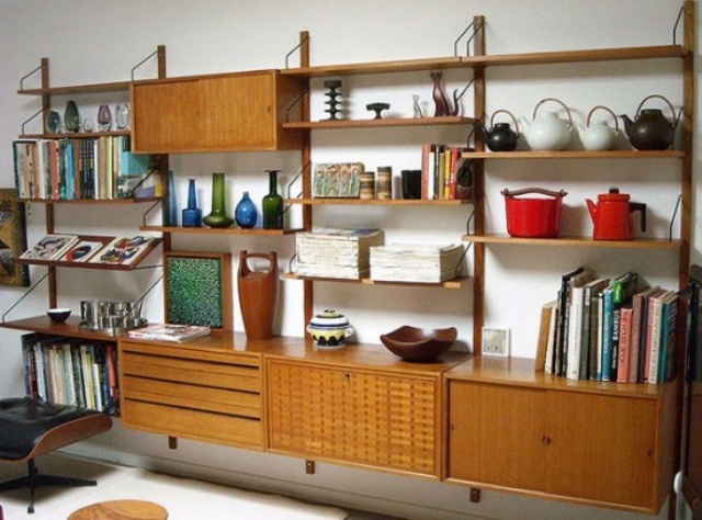 A large wall mounted storage unit with cabinets, drawers and shelves including slanted ones, all placed symmetrically