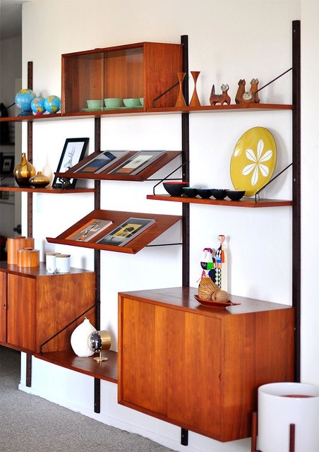 A mid century modern wall unit with open shelves, cabinets and slanted shelves of a rich stain color