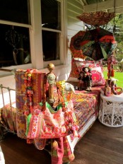 a boho porch with a sleeping nook – metal furniture with colorful printed textiles, bright umbrellas and a white table with toys