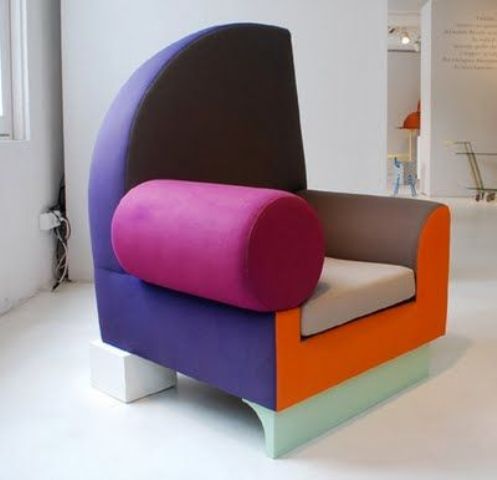 a color block armchair with mismatching armrests, with a violet back, a grey seat, a fuchsia armrest and a pastel green base will make a  statement