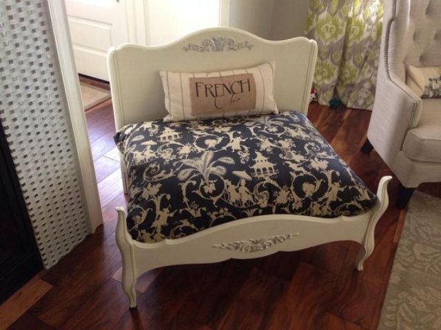 A vintage inspired white dog bed with a printed mattress and a pillow is a very refined solution to rock