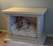 a vintage white cabinet turned into a little dog bed, with a large cushion and a favorite toy is ideal for a bedroom