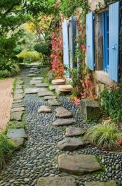 a black and grey gravel path with large rough stones on top that add eye-catchiness and a bold touch to the space
