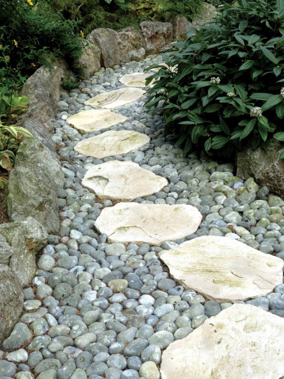 grey pebbles and rough stones and rocks that create a border of the path, a natural and fresh look for every garden