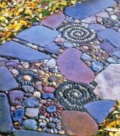 a bold garden path with muted color stones and pebbles that form floral and swirl patterns looks very eye-catching