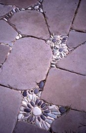 a rough stone pathway with small pebble flower inserts in it that make it bolder and cuter