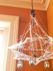 a unique Halloween chandelier with faceted lanterns, spiderwebs, rope and spiders is a cool idea for a Halloween space