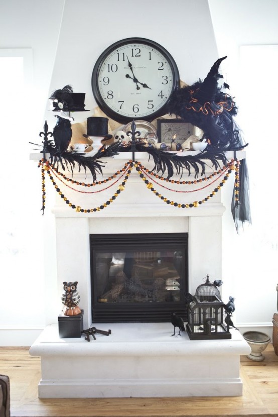a Halloween mantel with black witches' hats, blackbirds, banners and garlands, feathers and a vintage clock