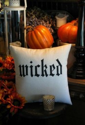 a black and white Halloween pillow and orange pumpkins are a great combo for Halloween decor – it’s easy and nice
