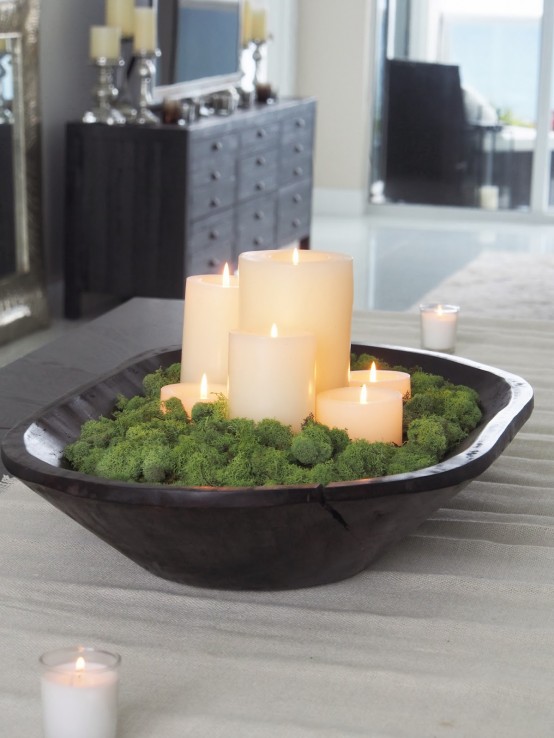 a dark stained dough bowl with moss and pillar candles is a cool centerpiece with a fresh feel