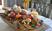 a wild fall centerpiece of a dough bowl, pinecones, moss, faux pumpkins and mushrooms plus some hay