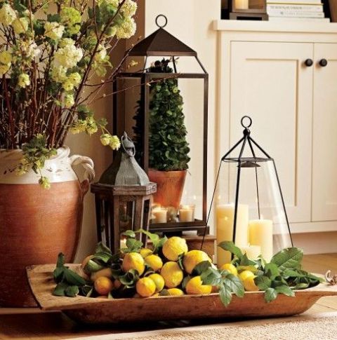 a vintage rustic decoration of a dough bowl, lemons, greenery and a couple of candle lanterns