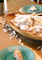 a dough bowl with seashells and starfish is a simple and stylish centerpiece for a coastal home