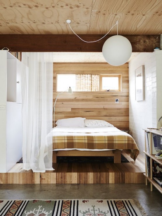 a plywood platform and a matching headboard wall highlight the bedroom space