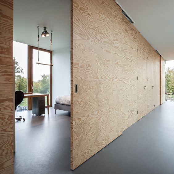 a large plywood sliding door matches a minimalist space and makes it cooler