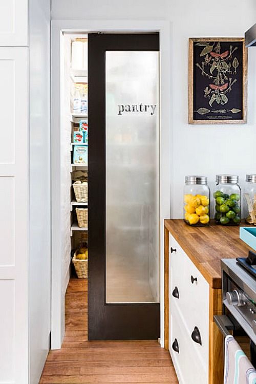 a frosted glass sliding door with dark framing and a word that marks the space behind it - a pantry