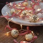 a porcelain tray with lights and Christmas bells with plaid ribbons is a very cool and cozy modern Christmas decor idea