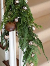railing decorated with fir branches and silver bells for Christmas – natural and traditional at the same time